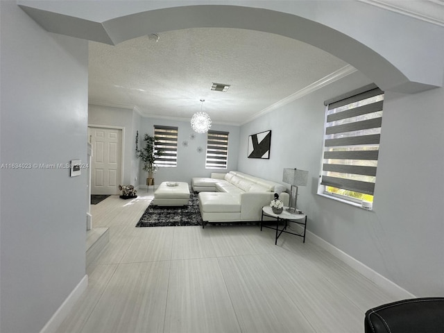 living room with an inviting chandelier, tile patterned floors, a textured ceiling, and crown molding