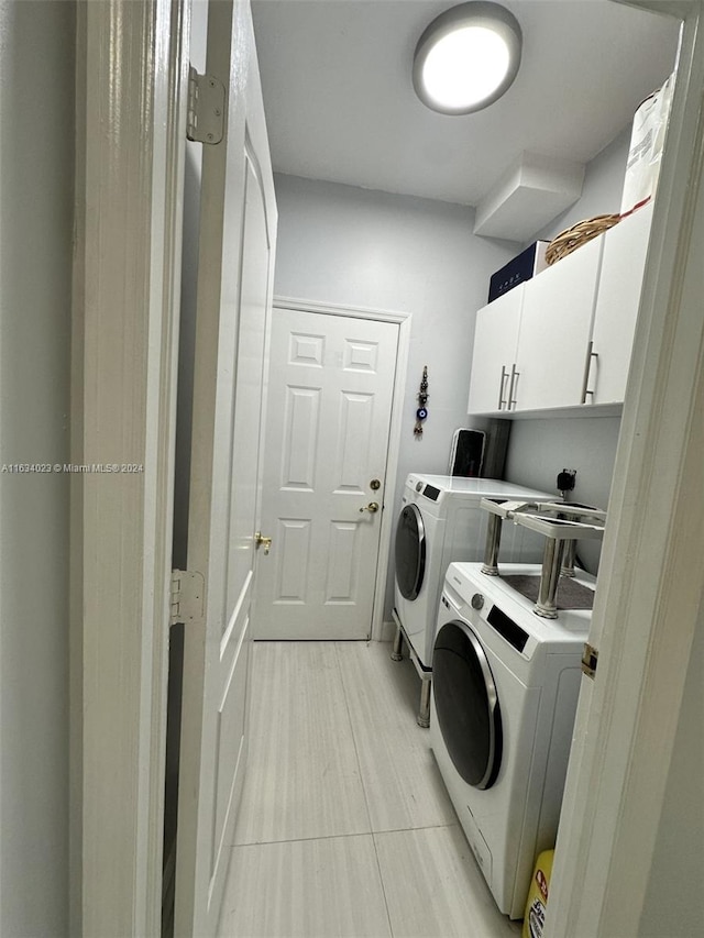 washroom with washing machine and dryer, cabinets, and light tile patterned floors