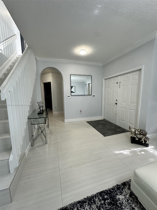 tiled foyer featuring a textured ceiling and ornamental molding