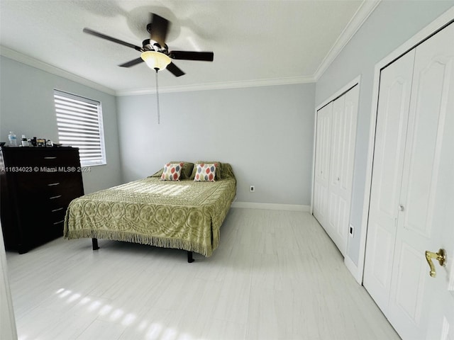 bedroom with two closets, ceiling fan, and ornamental molding