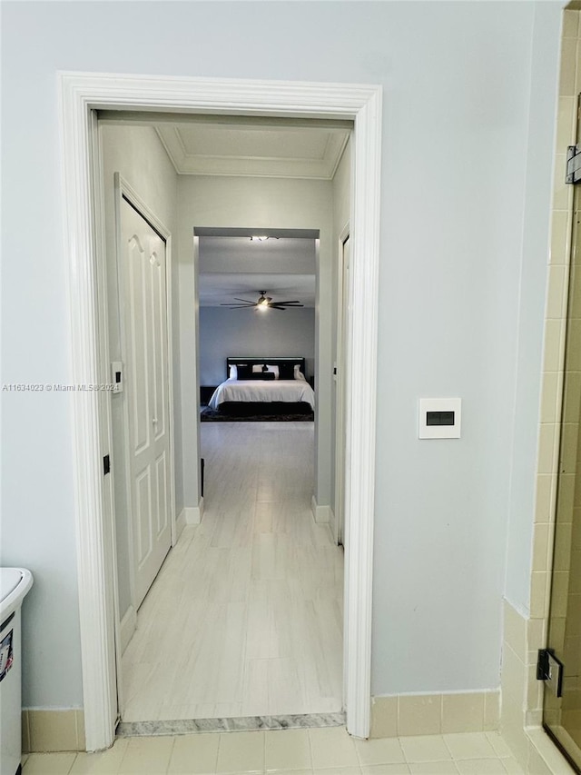 corridor featuring ornamental molding and light tile patterned flooring