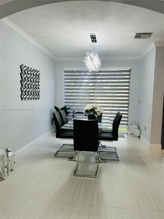 dining area featuring a chandelier, a textured ceiling, ornamental molding, and light tile patterned floors