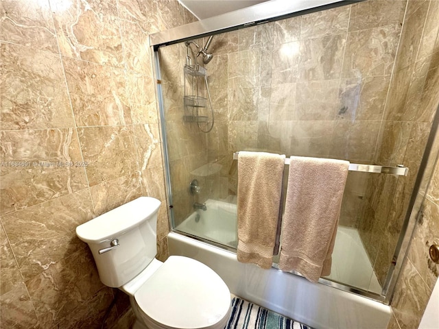 bathroom with toilet, combined bath / shower with glass door, and tile walls