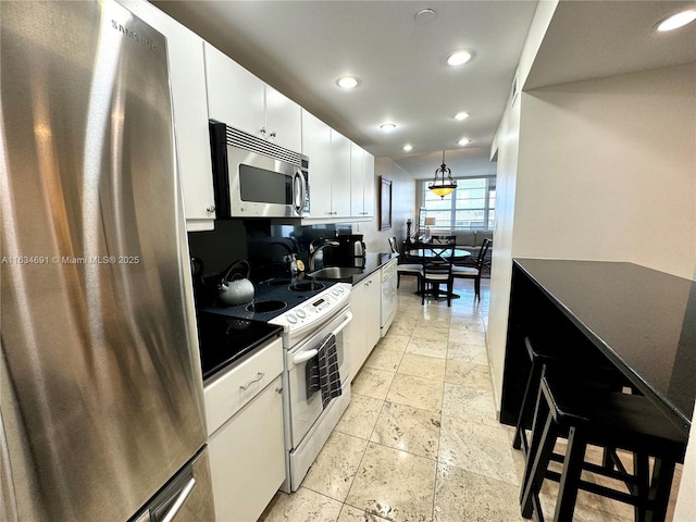 kitchen featuring pendant lighting, sink, a breakfast bar area, appliances with stainless steel finishes, and white cabinetry