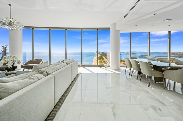 tiled living room featuring an inviting chandelier, a water view, and a wall of windows