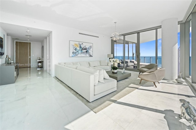 tiled living room with a notable chandelier, a wall of windows, and a water view