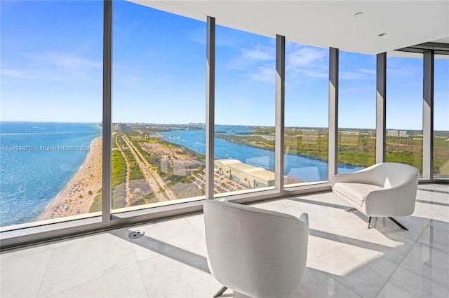 unfurnished sunroom with a wealth of natural light, a view of the beach, and a water view