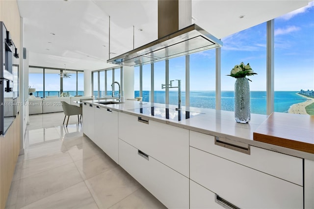 kitchen with white cabinetry, light tile patterned floors, a water view, black electric stovetop, and sink