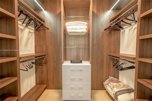 walk in closet with light hardwood / wood-style floors