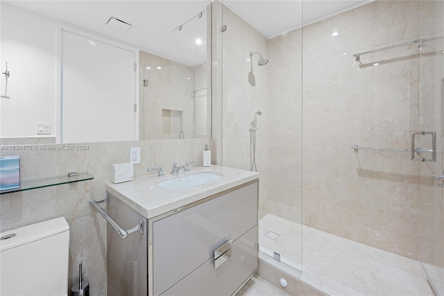 bathroom with a shower with shower door, vanity, tile walls, and toilet