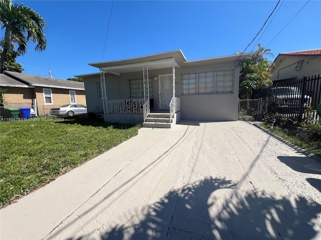 view of front of house with a front yard, fence, a porch, and stucco siding