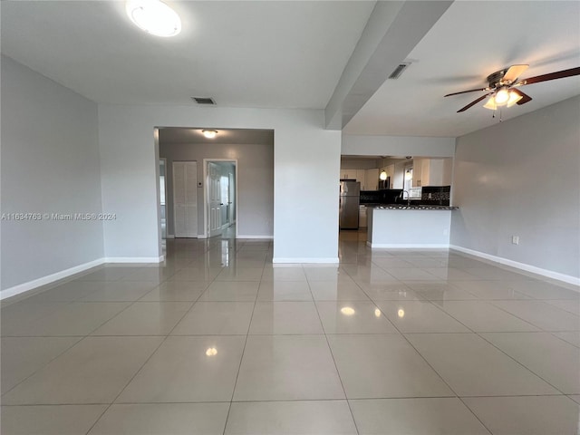 empty room with a ceiling fan, visible vents, baseboards, and light tile patterned flooring