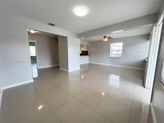 tiled empty room featuring a healthy amount of sunlight, visible vents, and baseboards