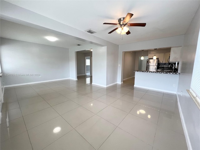 unfurnished living room featuring light tile patterned floors, visible vents, baseboards, and ceiling fan