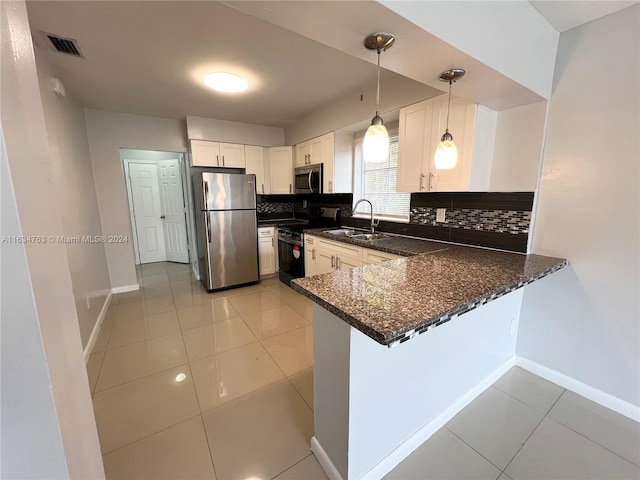 kitchen featuring a peninsula, tasteful backsplash, appliances with stainless steel finishes, and a sink