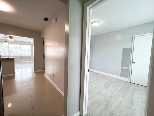 hall featuring visible vents, light wood-style flooring, and baseboards