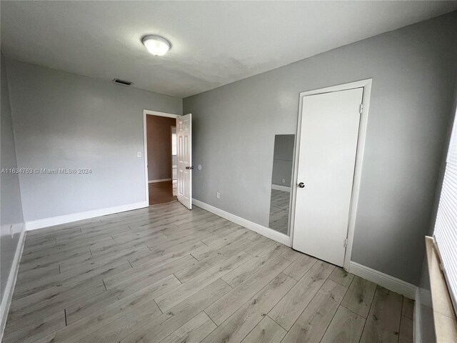 unfurnished bedroom with a closet and light hardwood / wood-style floors