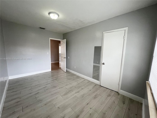 spare room with light wood finished floors, visible vents, and baseboards