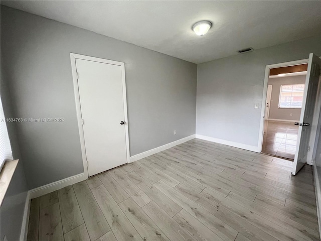 empty room featuring wood finished floors, visible vents, and baseboards