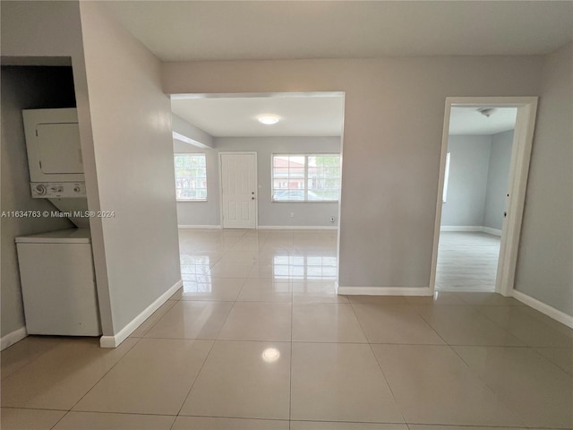 hall with light tile patterned floors, baseboards, and stacked washer / drying machine