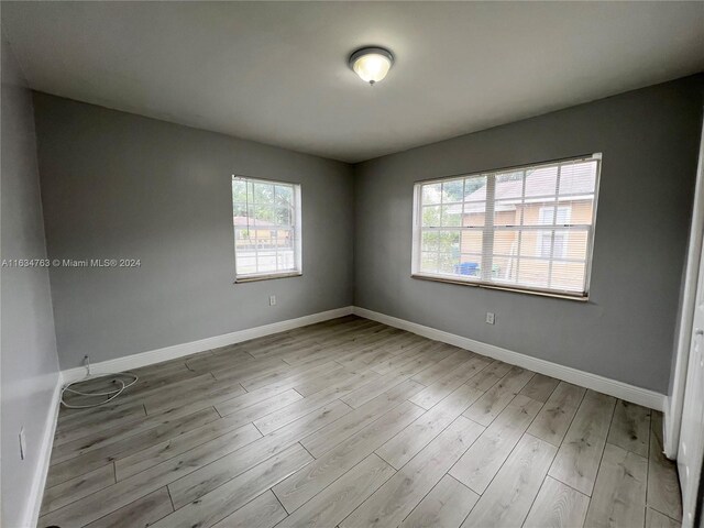 spare room with plenty of natural light and light hardwood / wood-style flooring