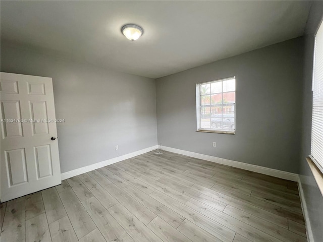 spare room with baseboards and wood finished floors