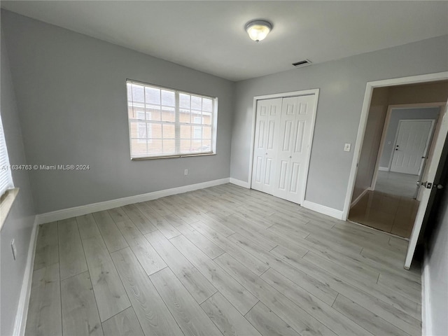 unfurnished bedroom featuring a closet, wood finished floors, visible vents, and baseboards