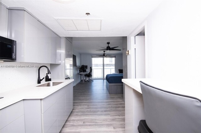 kitchen with ceiling fan, sink, gray cabinets, and hardwood / wood-style floors