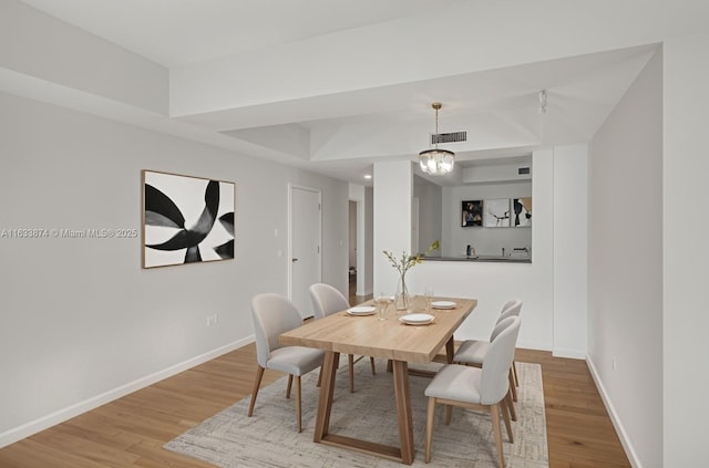 dining space featuring wood finished floors, baseboards, and a chandelier