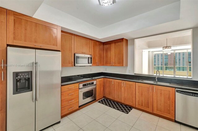kitchen with appliances with stainless steel finishes, a sink, dark countertops, and brown cabinets