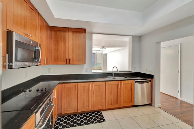 kitchen with appliances with stainless steel finishes, a sink, and brown cabinetry