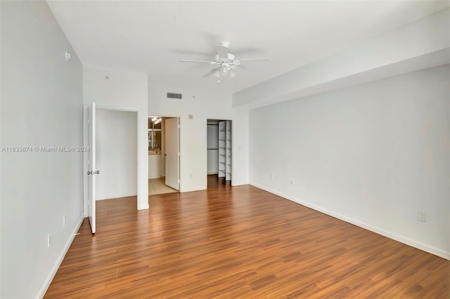 unfurnished bedroom featuring ceiling fan, wood-type flooring, and ensuite bath