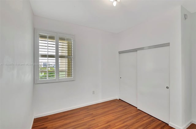 unfurnished bedroom featuring a closet, baseboards, and wood finished floors