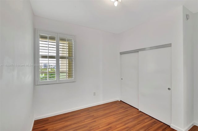 unfurnished bedroom with wood finished floors, a closet, and baseboards