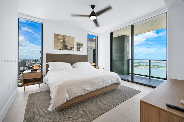 bedroom with light tile patterned flooring, ceiling fan, a water view, access to exterior, and floor to ceiling windows