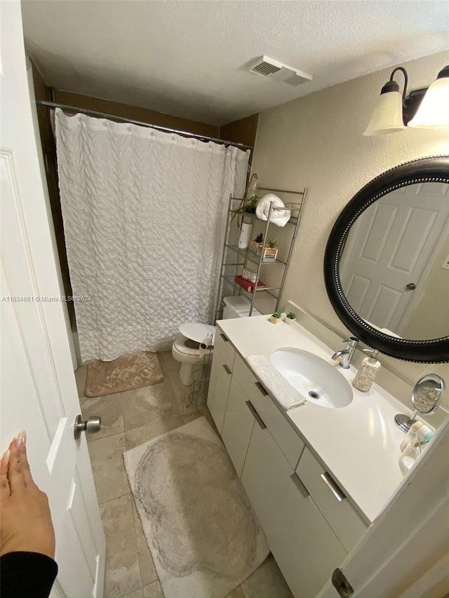 bathroom featuring vanity, a textured ceiling, toilet, and tile patterned floors