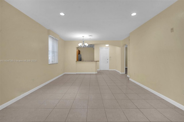 spare room with light tile patterned flooring and an inviting chandelier