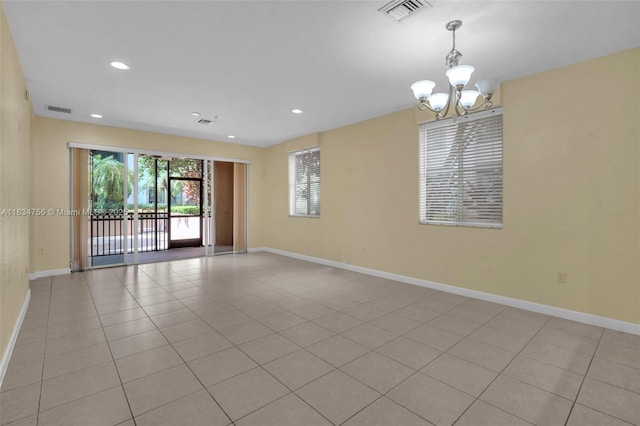 spare room featuring light tile patterned floors and an inviting chandelier