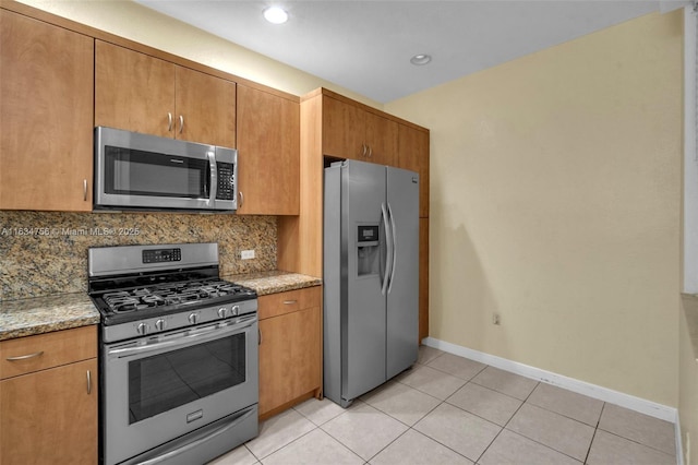 kitchen with decorative backsplash, light stone counters, light tile patterned floors, and stainless steel appliances