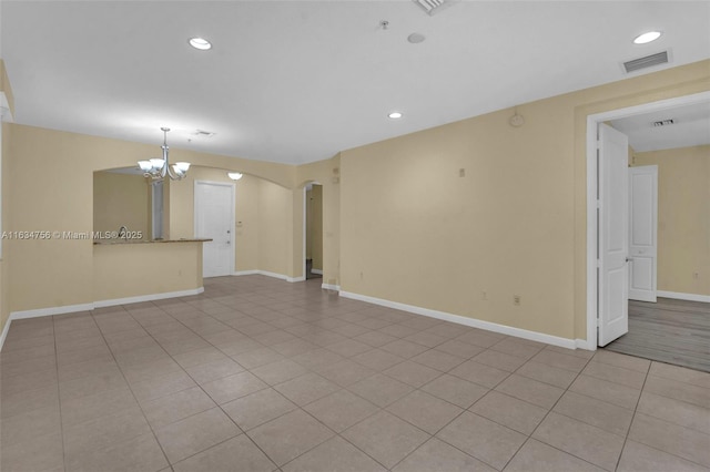 unfurnished living room with a chandelier and light tile patterned floors