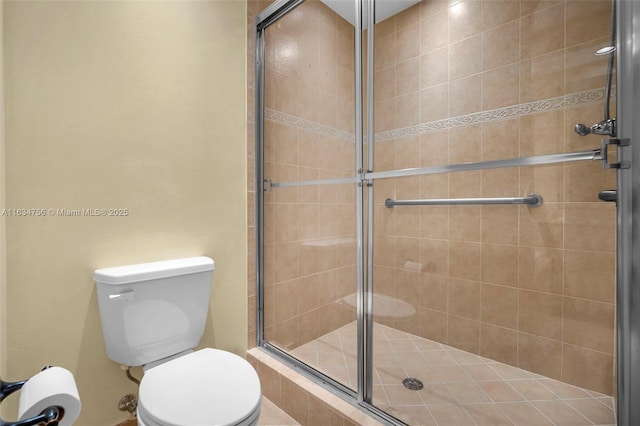 bathroom with a shower with shower door and toilet