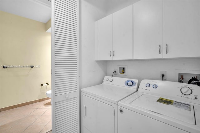 laundry area with washer and clothes dryer, light tile patterned floors, and cabinets