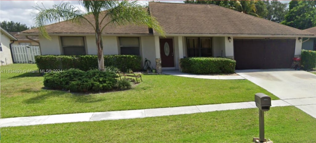 ranch-style home featuring a garage and a front yard