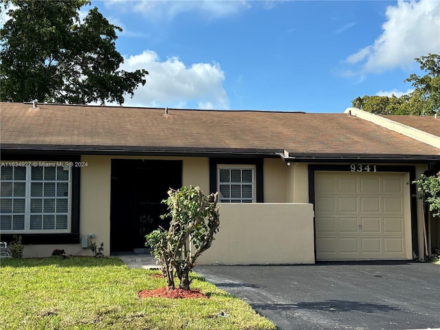 single story home featuring a garage and a front lawn