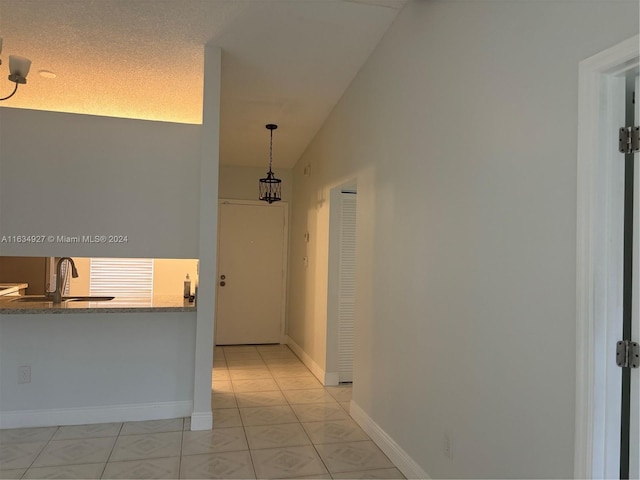 corridor with a textured ceiling, sink, and vaulted ceiling