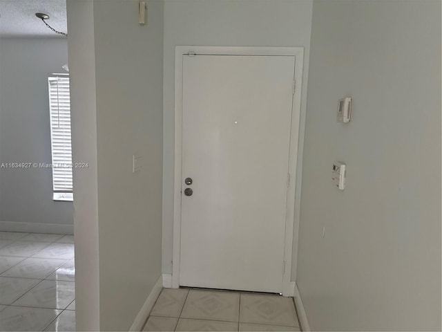 doorway to outside with a textured ceiling and light tile patterned flooring