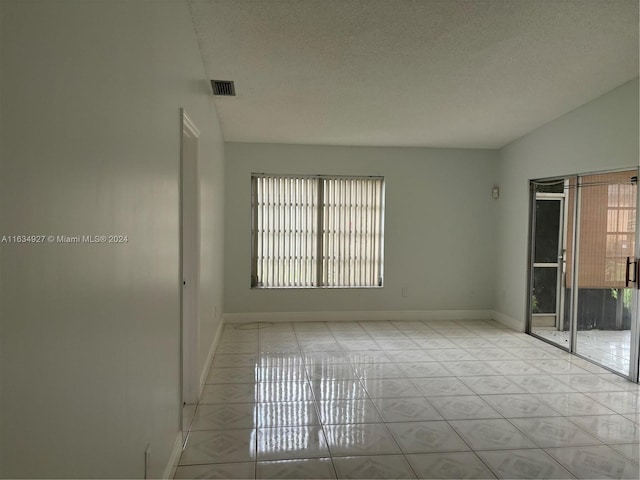 unfurnished room with lofted ceiling, a textured ceiling, and a healthy amount of sunlight