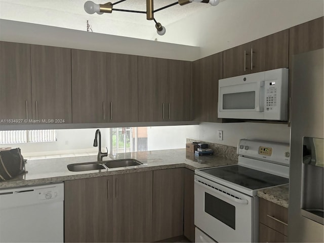 kitchen featuring light stone countertops, white appliances, and sink