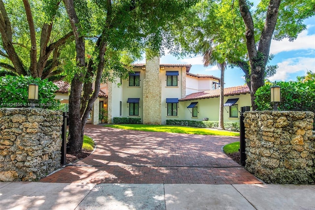 view of front of home with stucco siding, decorative driveway, and a tile roof