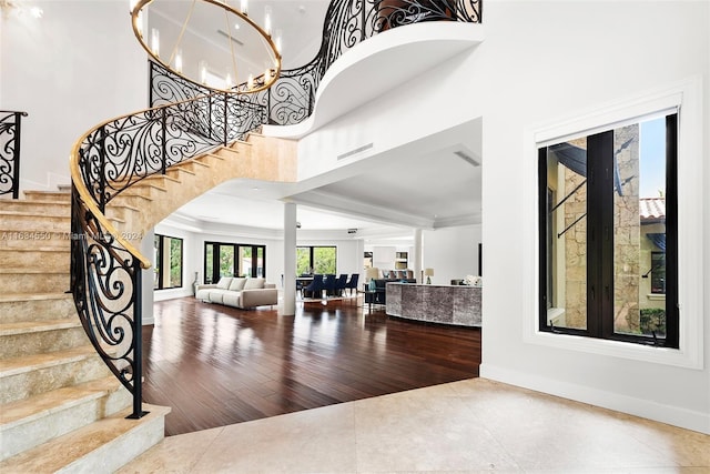 foyer featuring wood finished floors, ornamental molding, baseboards, stairway, and a high ceiling